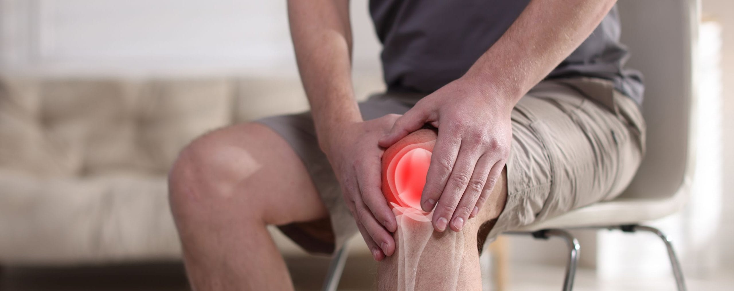 Person sitting on a chair while experiencing chronic knee pain