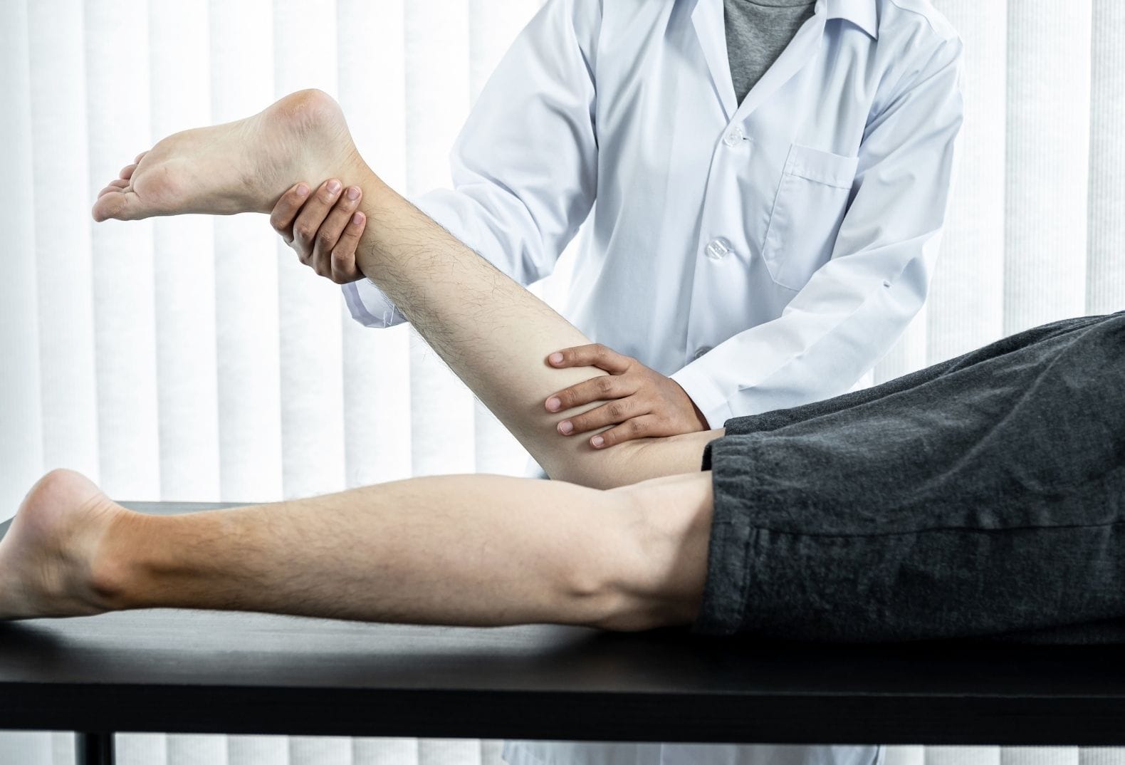 physiotherapist performing sports rehabilitation exercises for a patient